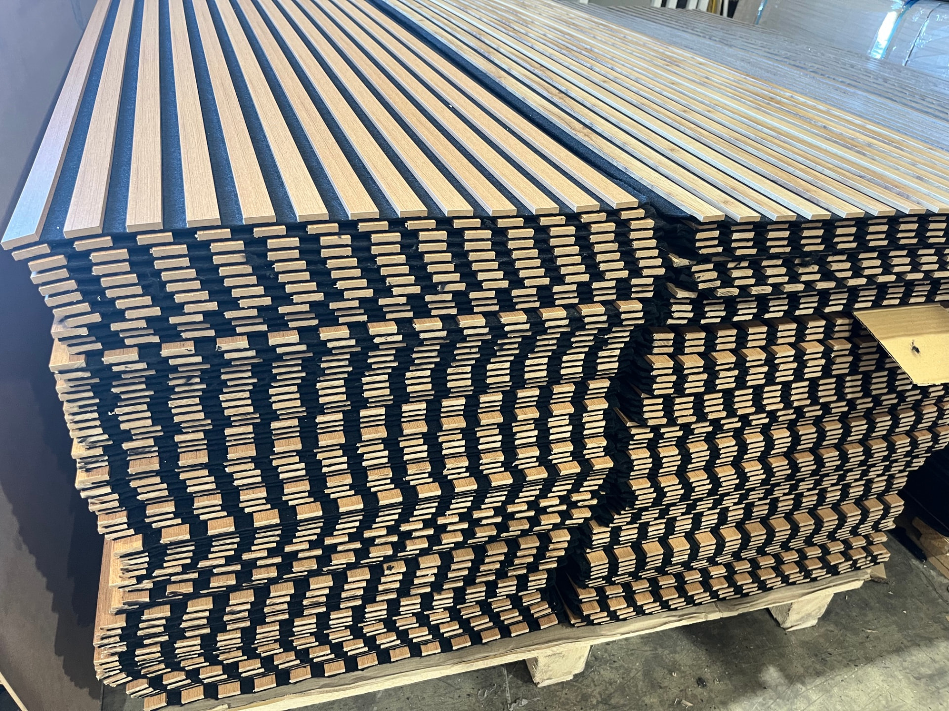 Panneaux muraux acoustiques finition chêne empilés sur une palette d'export en bois