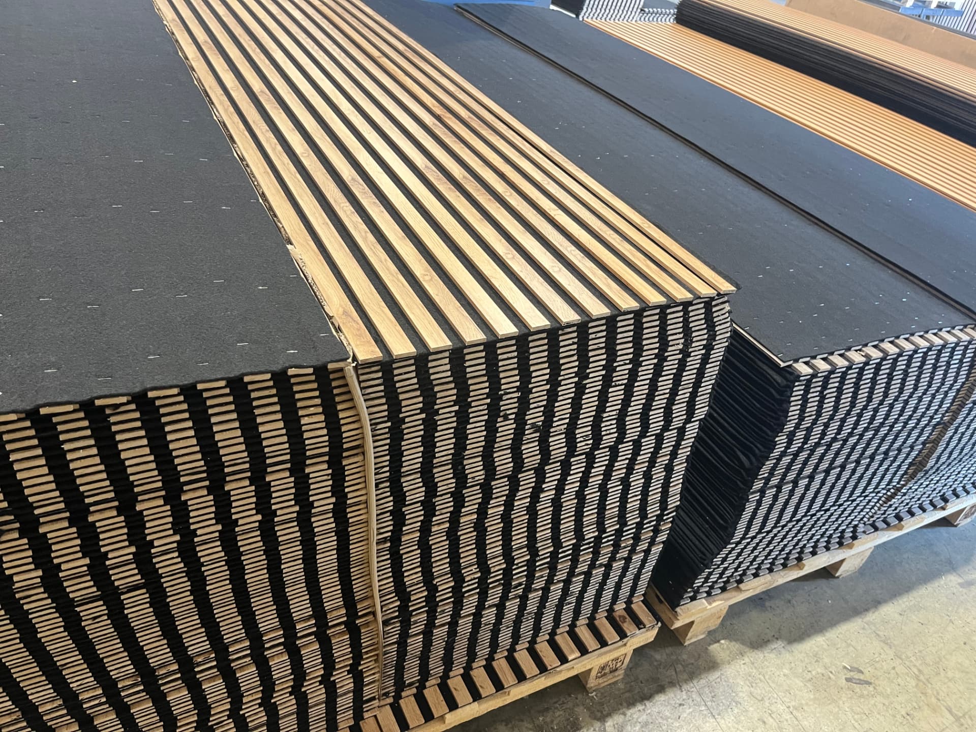 Palettes de panneaux acoustiques finition teck empilées dans l'entrepôt d'expédition SONAVEERS
